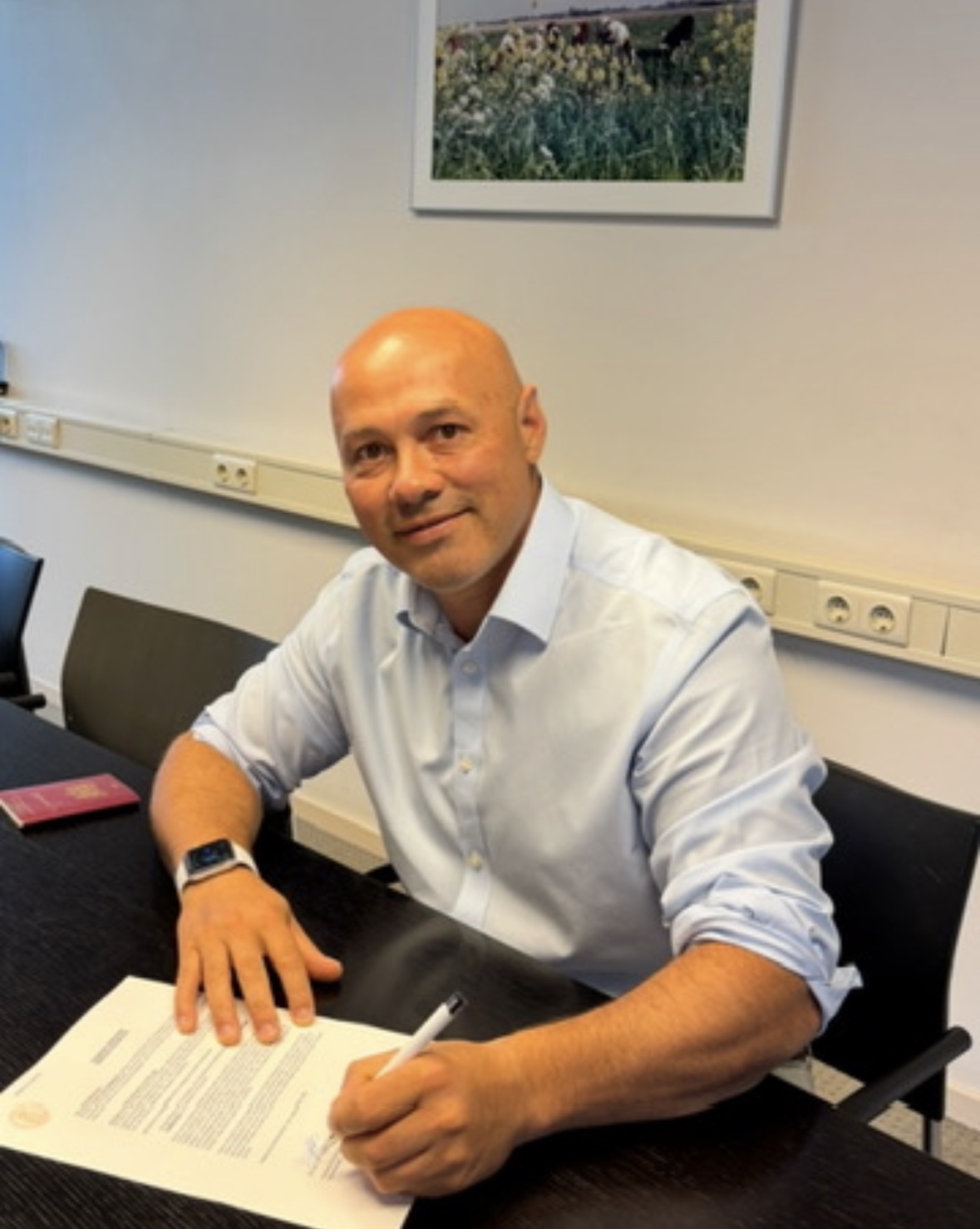 David Wielandt in een lichtblauw overhemd aan een vergadertafel, met een document voor zich